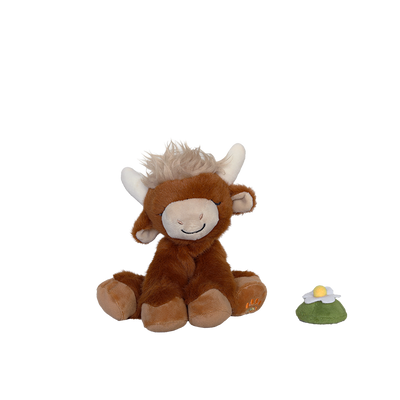 Plush toy cow with a small green and yellow object on a white background