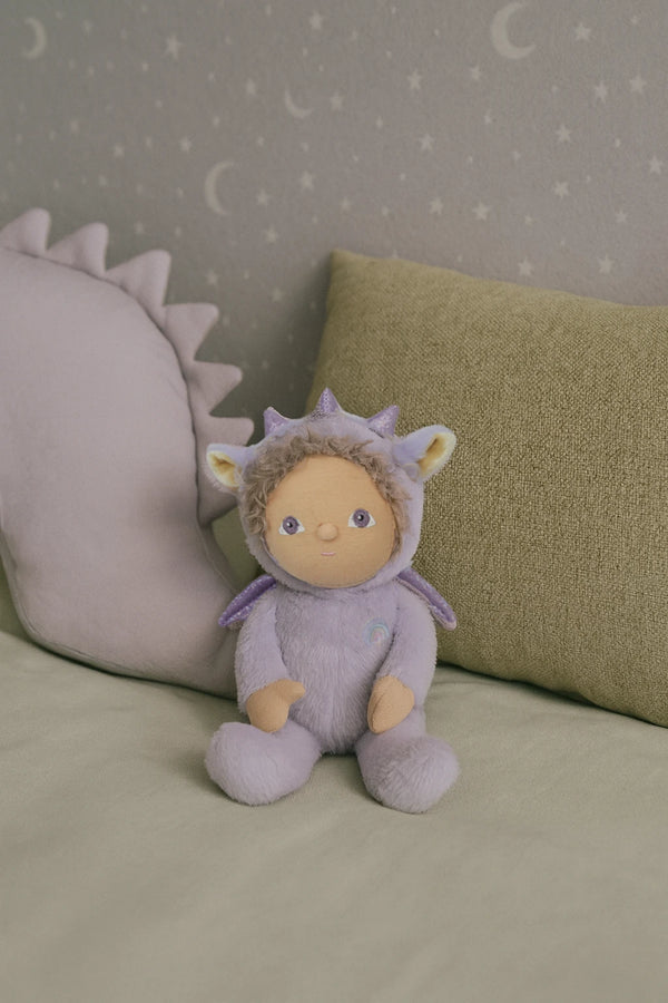Stuffed toy in a dinosaur costume sitting on a bed with a star-patterned wall in the background.