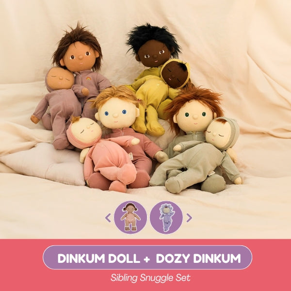 Set of soft toy dolls in various colors on a beige blanket with 'Dinkum Doll + Dozy Dinkum' branding.