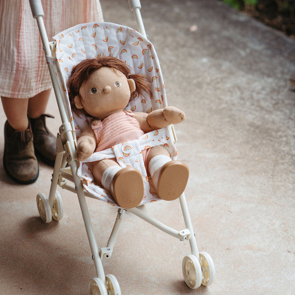 Doll in a small stroller with a child's feet visible in the background