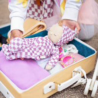 Olli Ella Dozy Dinkum Doll - Plum Check. Floppy soft-doll suitable from birth with purple check printed onesie, perfect for kids doll play.