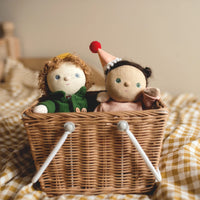 Two dolls in a wicker basket on a checkered blanket