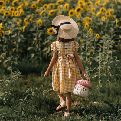 Olli Ella Rattan Mushroom Basket - musk and white coloured in field of sunflowers