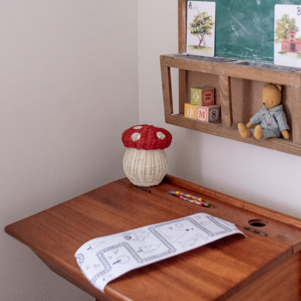 red and white rattan kids mushroom basket with coloured pencils for indoor play.