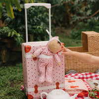 pink kids travel suitcase with strawberry print and matching doll.