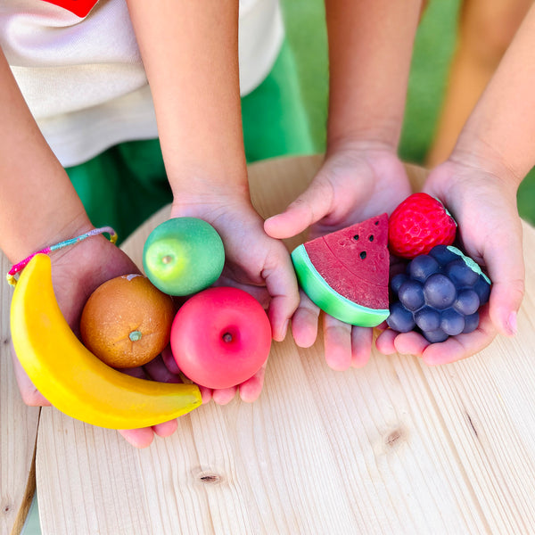 Olli Ella Tubbles Sensory Stones Fantastic Fruit held in children's hands